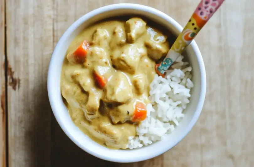 Korma de poulet pour bébé avec riz émietté : sauce crémeuse claire, petits morceaux tendres et légumes, texture parfaite pour l'apprentissage